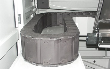 Artık yanık izi yok: özel "igumid HT" malzemesinden üretilmiş polimer hareketli kablo borusu. Enerji beslemesi, 850°C'ye varan taşlama talaşına karşı dirençlidir.